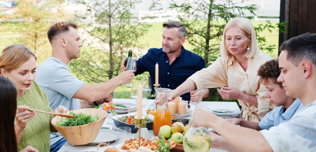 familie mit 8 personen sitzt am gartentisch